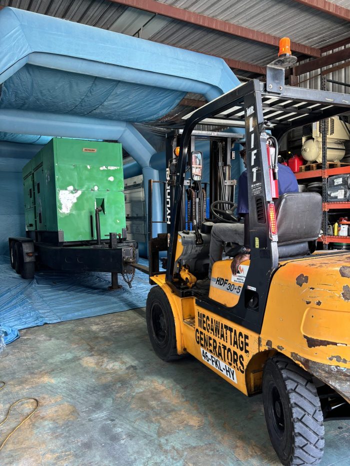 MegaWattage Team Member Uses Fork Lift To Place An Older Generator Inside The Inflated Tent For A Fresh Coat Of Paint.