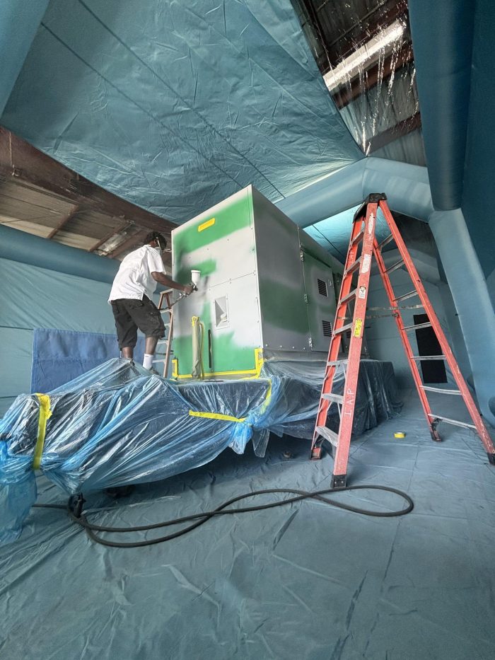 MegaWattage Team Member Covering The Green Generator With A Fresh Coat Of White Paint.