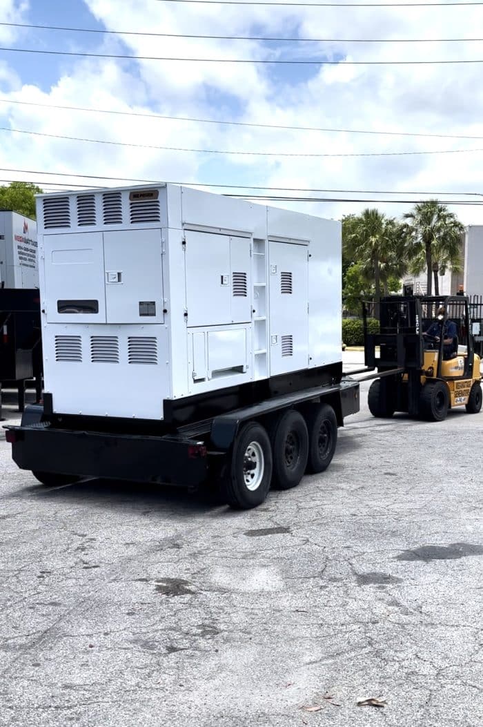 MegaWattage Team Member Using Forklift To Pull Freshly Painted Commercial Generator Outside Where The Other Generators Are Held.